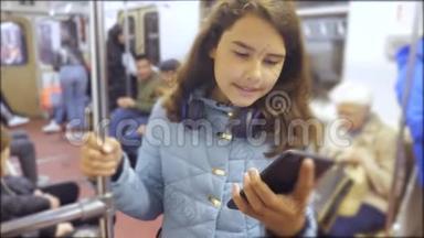 十几岁的女孩带着智能手机和耳机在地铁里，很多人挤在地铁里。 地铁